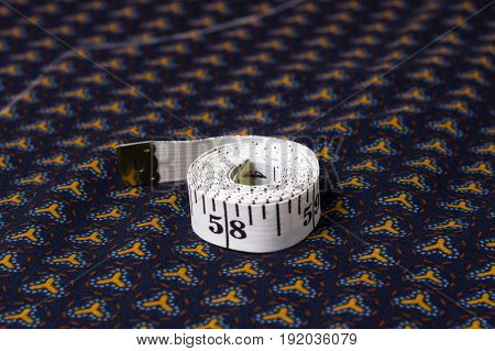 Inch, Centimeter Tape On A Background Of Blue Fabric With A Pattern