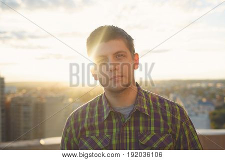 Portrait of a roofer top man on the roof at sunset at sunset. Courage and adrenaline. Loneliness and calmness.