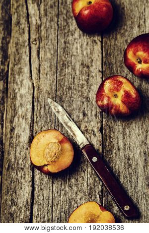 Ripe juicy peaches whole and slices and knife on old rustic wooden table. Selective focus. Toned image