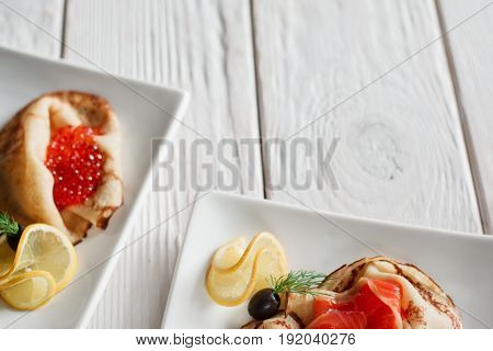 Set of dessert pancakes with seafood on white wooden background with free space. Russian traditional salty crepes with seafood. Shrove tuesday holiday food