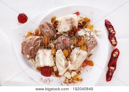 Halva, dried apricots, raisins, walnuts, churchchel, marmalade in powdered sugar. Oriental sweets on a plate