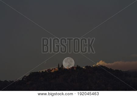 Supermoon setting over Buddhist temple on mountain at early morning focus at temple