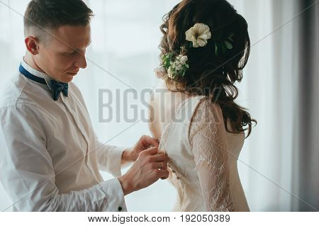 The groom dresses the bride. Wedding preparations