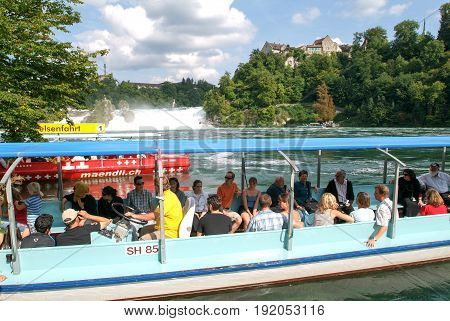 People In A Tourist Boat Approaching The Rhine Waterfalls