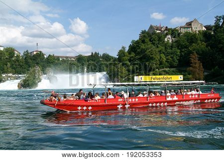 People In A Tourist Boat Approaching The Rhine Waterfalls