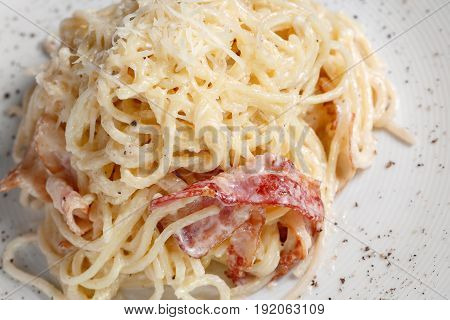 Pasta Carbonara. Spaghetti with bacon, parsel and parmesan cheese. Pasta Carbonara on white plate with parmesan. Italian psta food concept.