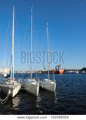 Symmetrical lineup of white sailboats with reflection