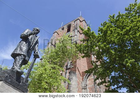 statue of troelstra next to oldehove tower in the centre of leeuwarden capital of friesland in the netherlands with blue sky