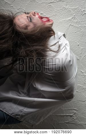 screaming crazy woman with flying hair in straitjacket