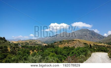 The view towards the Kourtaliotiko gorge in Crete. Mountains, fields, trees and road