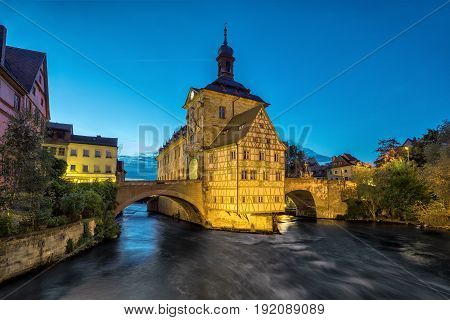 Bamberg. Illuminated building of Old Town Hall of Bamberg (Altes Rathaus) with two bridges over the Regnitz river in the evening Germany