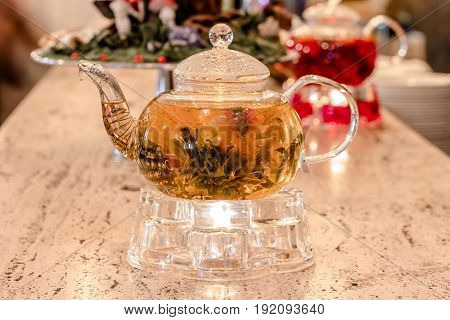 Glass teapot with green tea on a stand