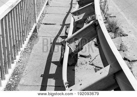 Damaged security steel fence on the bridge from car crash accident. Selective focus. Black and white.