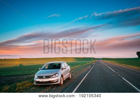 Gomel, Belarus - May 11, 2017: VW Volkswagen Polo Vento Sedan Car Parking Near Asphalt Country Road In Sunny Morning Or Evening. Road At Sunny Sunset Or Sunrise Under Dramatic Sky At Spring Or Summer