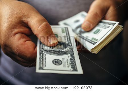 Man giving hundred us dollar banknote and holding cash in hands. Money credit concept, Selective focus