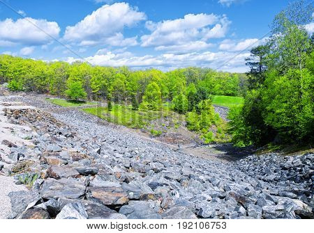 The rocky side of Hop Brook Dam in Naugatuck connecticut on a sunny blue sky day.