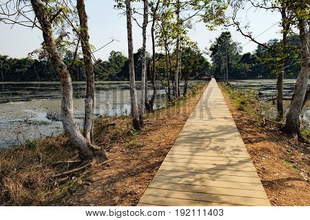 Mysterious wooden path towards Neak Pean Temple through artificial island in Angkor Complex, Siem Reap, Cambodia. Ancient Khmer architecture, famous Cambodian landmark, World Heritage