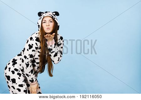 Happy teenage girl in funny nightclothes pajamas cartoon style sending kiss positive face expression studio shot on blue.