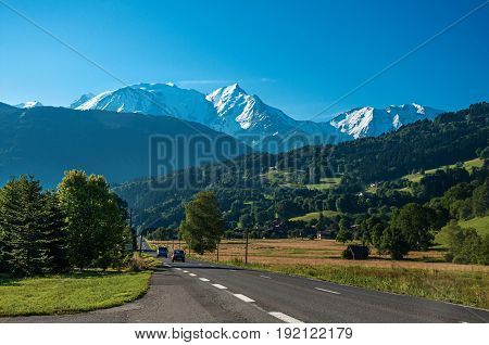 Fields, road, forest, alpine landscape and blue sky in the background, Saint-Gervais-Les-Bains, French Alps