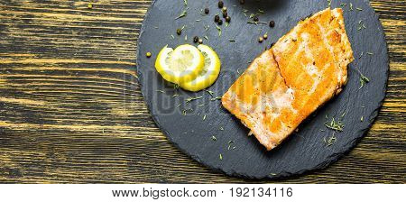 Grilled salmon steak with fresh lemon top view.