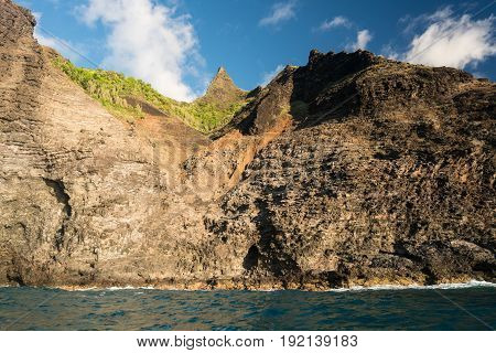 Kalalau trail path crosses steep ridge on Na Pali coastline in Kauai from sunset cruise