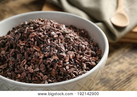 Cocoa nibs in bowl on wooden table