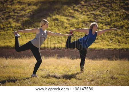 Beautiful women praising yoga during obstacle course in boot camp