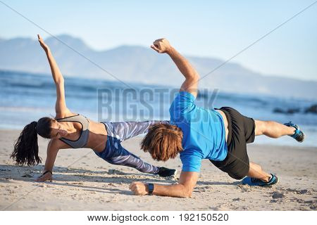 Fit couple doing intense workout on beach side planks strength training, healthy lifestyle