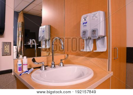UNITED STATES - June 19, 2017: Sink in a hospital room with hand sanitizer and soap dispensers, and toiletries.