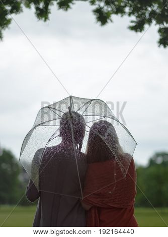 Two women walking park in rain and talk. Friendship and people communication. Rainy day in summer