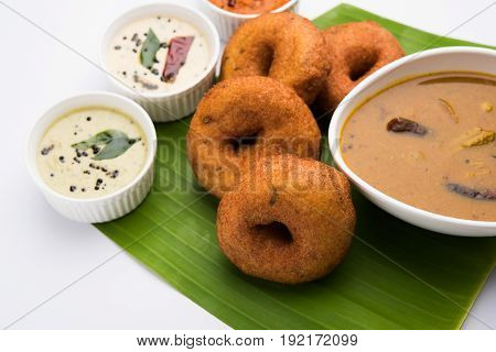 south indian food called vada sambar or sambar vada or wada, served with coconut, green and red chutney over fresg banana leaf, selective focus