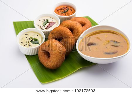 south indian food called vada sambar or sambar vada or wada, served with coconut, green and red chutney over fresg banana leaf, selective focus