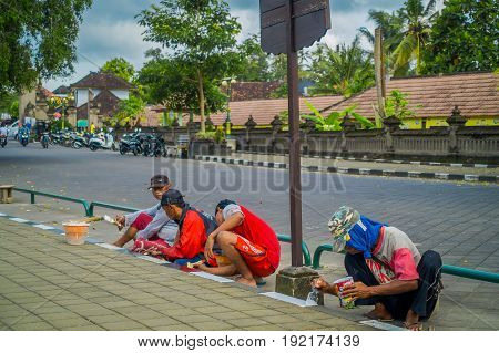 BALI, INDONESIA - MARCH 08, 2017: Unidentified group of people painting the sidewalk outside of the royal temple of Mengwi Empire located in Mengwi in Bali, Indonesia.