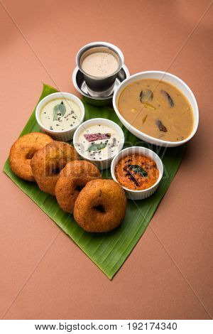 south indian food called vada sambar or sambar vada or wada, served with coconut, green and red chutney over fresg banana leaf, selective focus