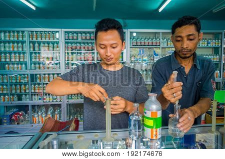 BALI, INDONESIA - MARCH 08, 2017: Unidentified man using syringes and pipettes mixing essences to prepare perfumes for the perfume store in Denpasar Indonesia.