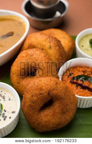 south indian food called vada sambar or sambar vada or wada, served with coconut, green and red chutney over fresg banana leaf, selective focus