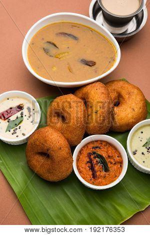 south indian food called vada sambar or sambar vada or wada, served with coconut, green and red chutney over fresg banana leaf, selective focus