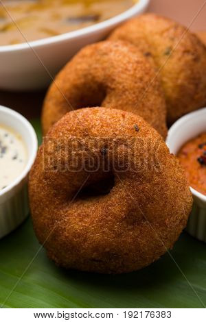 south indian food called vada sambar or sambar vada or wada, served with coconut, green and red chutney over fresg banana leaf, selective focus