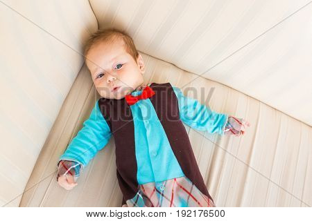Adorable baby boy with red hair and blue eyes. Newborn child lyling in couch