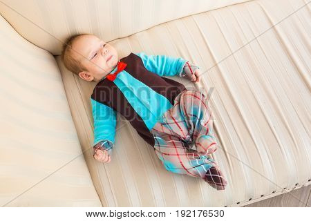 Adorable baby boy with red hair and blue eyes. Newborn child lyling in couch