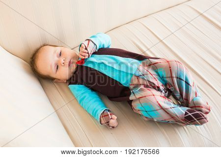 Adorable baby boy with red hair and blue eyes. Newborn child lyling in couch