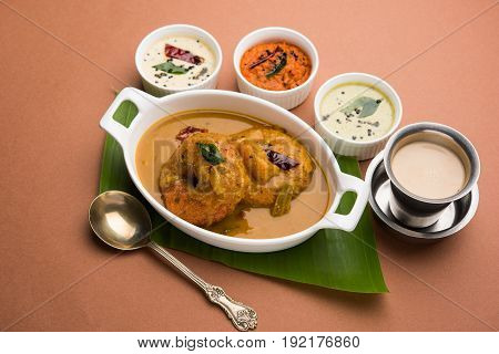 south indian food called vada sambar or sambar vada or wada dipped in sambar with coconut, green and red chutney and south indian style hot coffee, selective focus