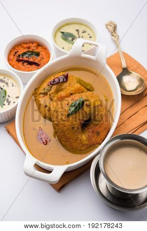south indian food called vada sambar or sambar vada or wada dipped in sambar with coconut, green and red chutney and south indian style hot coffee, selective focus