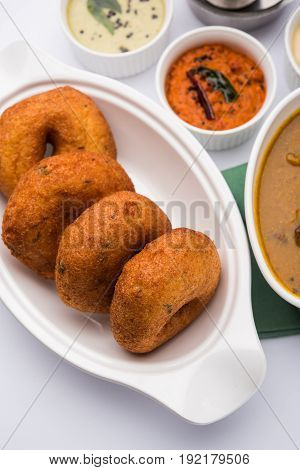 south indian food called vada sambar or sambar vada or wada, served with coconut, green and red chutney over fresg banana leaf, selective focus