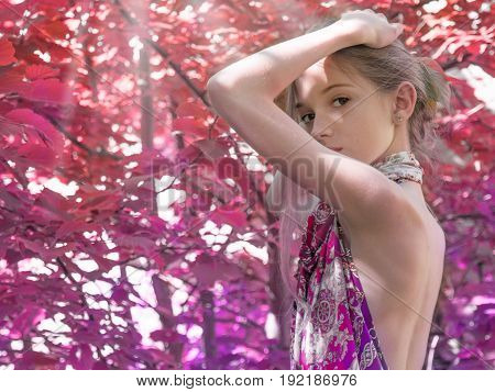 a young girl in a dress with nude backs worth in the foliage in the Woods, Red forest. hair decorated with foliage. in the sunlight.