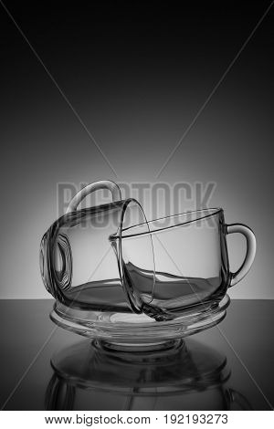 Two glass transparent cup for tea and an empty saucer on a black background