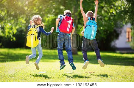 Children with rucksacks standing in the park near school. Pupils with books and backpacks outdoors