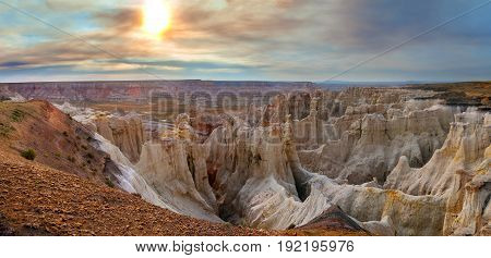 Enchanting view of Coalmine Canyon near Tuba City Arizona. It is late in the day and there was a nearby fire causing the sky to be filtered by colorful smoke.