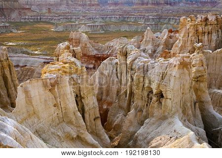Closeup of hoodoos at Coalmine Canyon near Page Arizona. The rock formations in the foreground are mostly white with hints of yellow and orange. The hill formations in the background are striped like the formation at Paria.