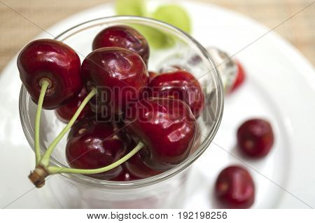 ripe cherry in a glass stands on a white plate